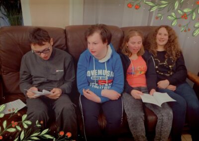 Grupa dzieci siedzących na kanapie i czytających materiały na spotkaniu z wychowawcą.