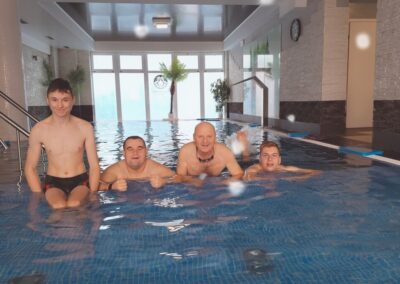 Grupa mężczyzn w basenie, stojących w wodzie podczas sesji pływackiej.