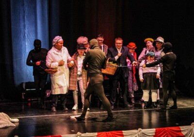 Grupa uczestników występująca na scenie, jedna osoba trzyma kosz.