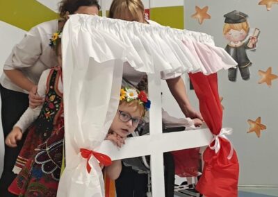 Dzieci bawią się przy dekorowanej scenie z elementami dziecięcymi i religijnymi w pomieszczeniu.