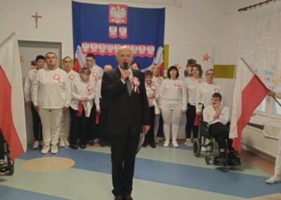 Osoby w biało-czerwonych strojach z flagami Polski, godło i napis "11 LISTOPADA" w tle.