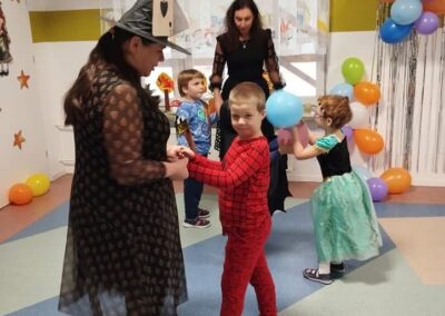 Dzieci na przyjęciu kostiumowym w pomieszczeniu z balonami i dekoracjami gwiazdkowymi.