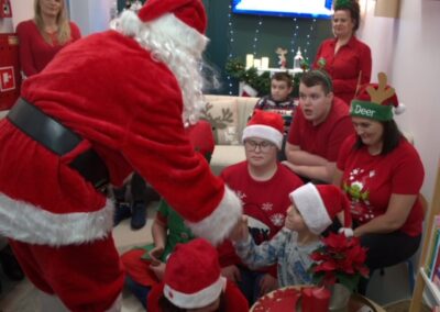 Mikołaj spotyka się z dziećmi w świątecznie udekorowanym pokoju podczas wydarzenia.