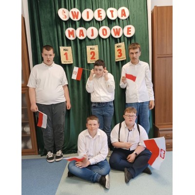 Grupa chłopców z flagami Polski przy dekoracji Święta Pracy, Dnia Flagi i Święta Konstytucji.