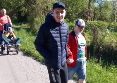 Dwóch mężczyzn idzie trzymając się za ręce, za nimi mężczyzna pcha wózek z dzieckiem.