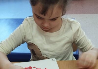 Dziewczynka wskazuje palcem na ilustrację konturu Polski z częściowo wypełnionymi kołami.
