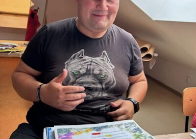Mężczyzna siedzi przy stole w poddaszu z książkami i materiałami do nauki.