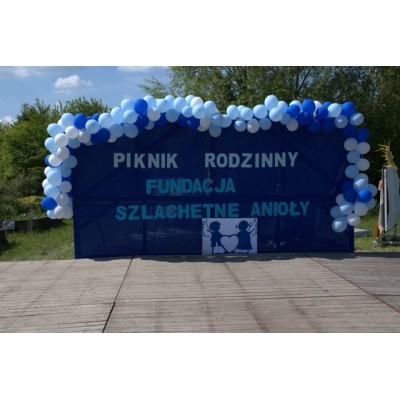 Baner Piknik Rodzinny Fundacja Szlachetne Anioły z niebiesko-białą girlandą balonów na drewnie.