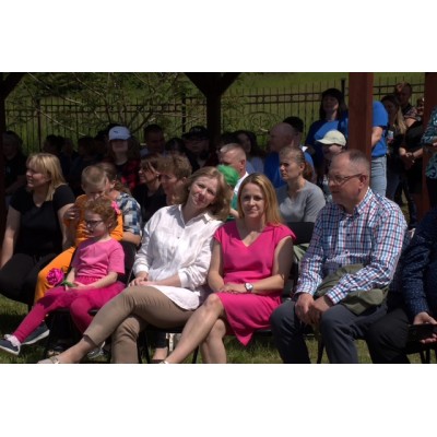 Ludzie siedzący na zewnątrz pod zadaszeniem podczas słonecznego wydarzenia.