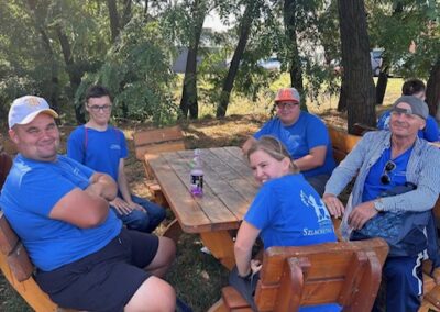 Uczestnicy wydarzenia maszerują na świeżym powietrzu w grupie, kontynuując trasę w słonecznej pogodzie.