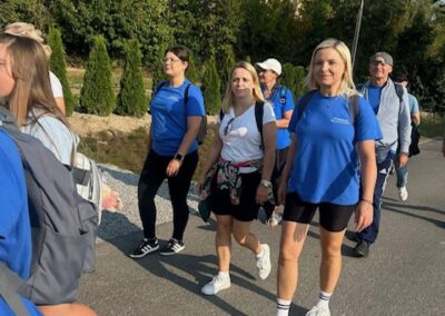 Zbliżenie na uczestników idących w grupie; na pierwszym planie osoba w niebieskiej koszulce i czapce z daszkiem.