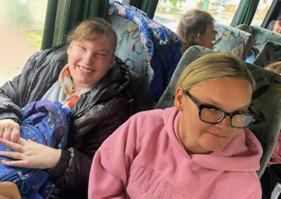 Wnętrze autobusu z pasażerami siedzącymi na fotelach, dwie kobiety na pierwszym planie.