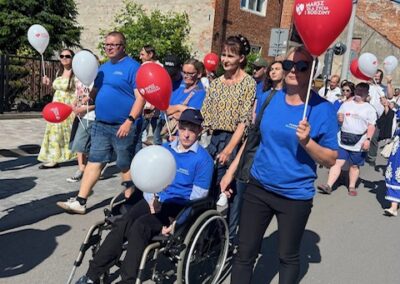 Marsz dla życia i rodziny z uczestnikami niosącymi czerwone i białe balony na ulicy.
