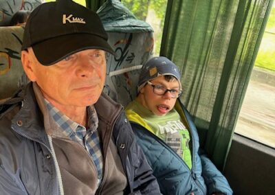 Mężczyzna w czapce z daszkiem i chłopiec w czapce i okularach siedzą obok siebie w autobusie.