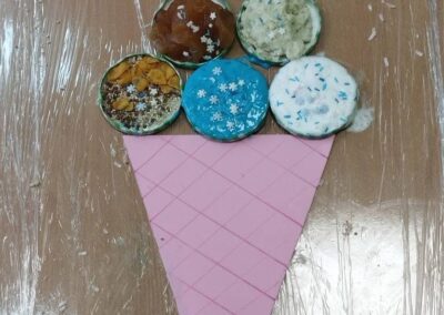 Widok z góry na papierowy rożek lodowy, na którym ułożono kolorowe kulki w zakrętkach posypane dekoracjami.