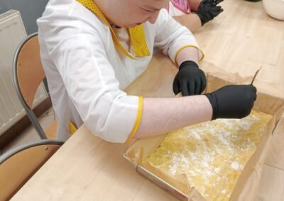 Uczestnik nakłuwa widelcem ciasto rozłożone w blaszce z papierem do pieczenia