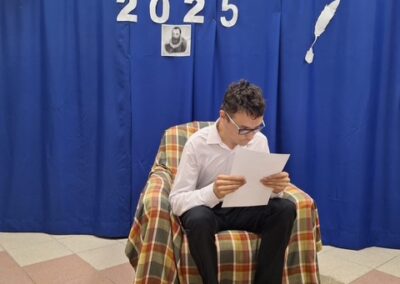 Chłopiec siedzi na fotelu i czyta książkę przed publicznością.