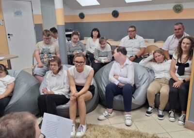 Grupa uczestników siedzi na kanapie i obserwuje przebieg czytania.