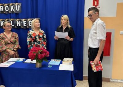 Zbliżenie na moment przekazania dyplomu lub nagrody podczas szkolnej uroczystości.