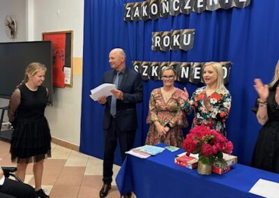 Uczeń otrzymuje dyplom od nauczyciela podczas zakończenia roku szkolnego na sali.