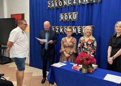 Uczeń prezentuje otrzymany dyplom na scenie w trakcie szkolnej uroczystości.