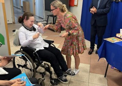 Nauczyciel wręcza dyplom uczniowi na wózku podczas zakończenia roku szkolnego.