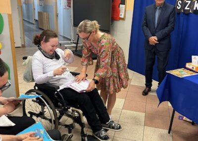 Grupa uczestników uroczystości stoi na sali szkolnej w trakcie zakończenia roku.