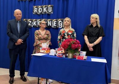 Grupa uczniów i nauczycieli na scenie po zakończeniu wręczania dyplomów.