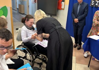 Uczeń i nauczyciel pozują do pamiątkowego zdjęcia po wręczeniu dyplomu na scenie.